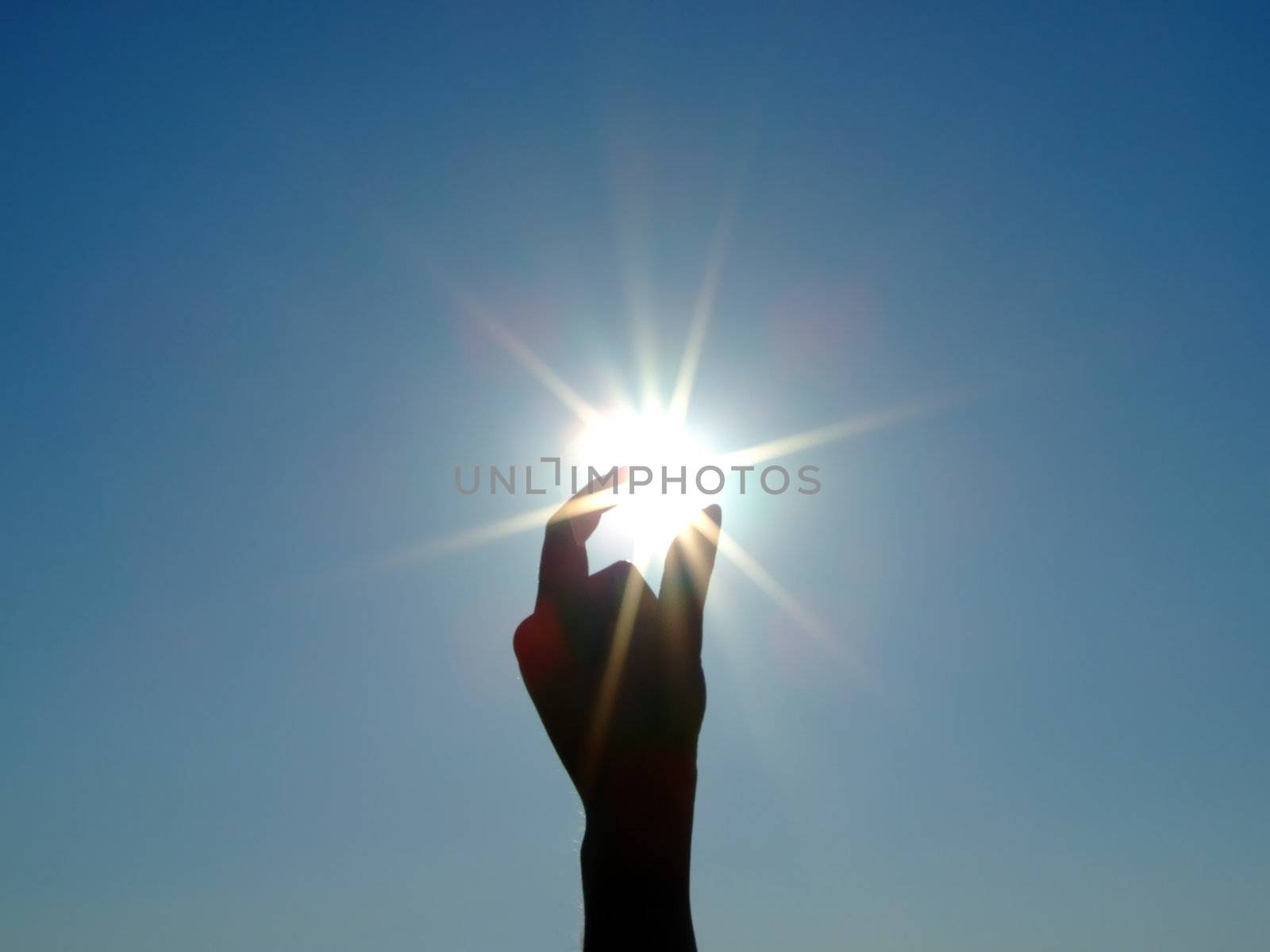 Silhouette of a female hand, the blue sky and the bright sun 2