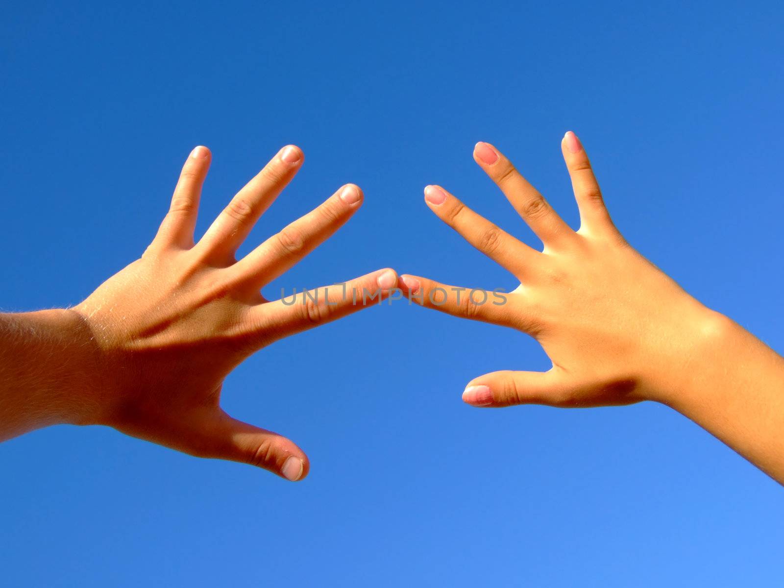 Man's and female hands on a background of the blue sky by acidgrey