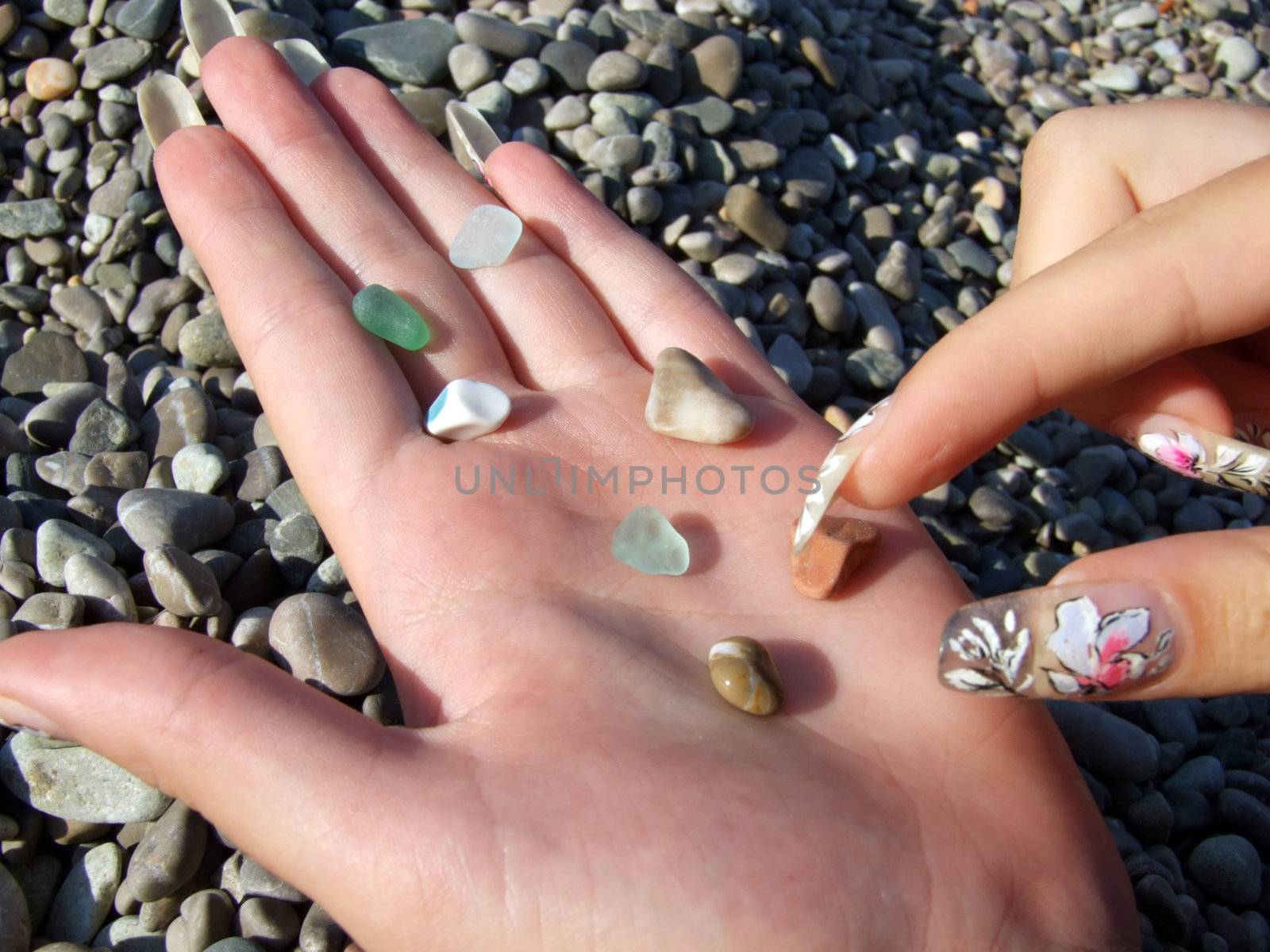 Multi-coloured pebble and glass on a female palm