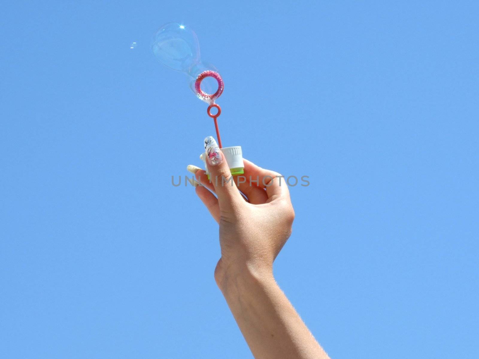 Female hand and soap bubbles on a background of the blue sky by acidgrey