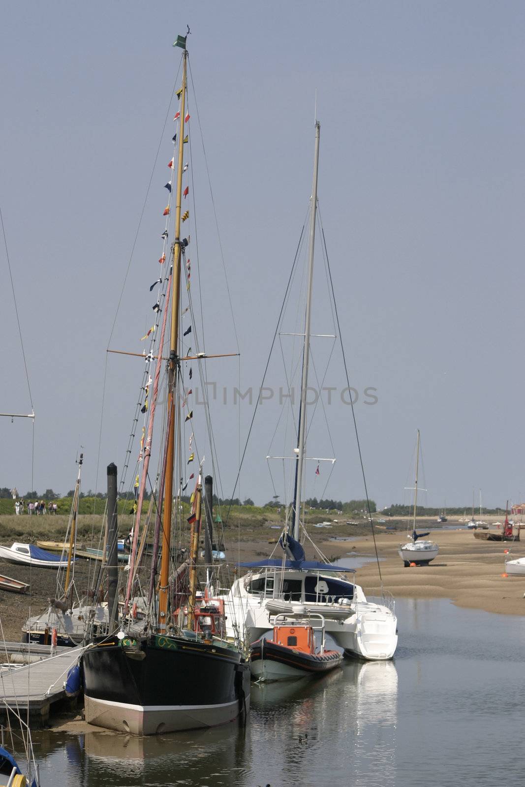 tall boats sitting at the quayside at low tide