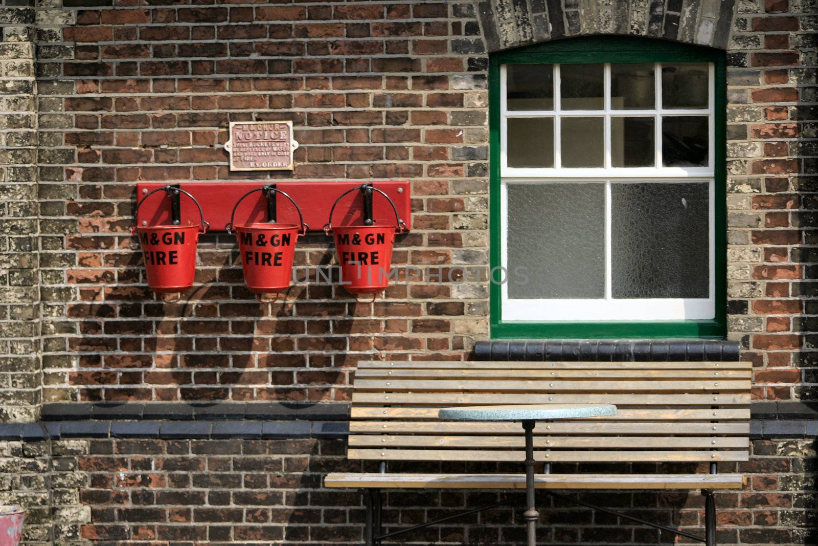 three fire buckets next to a window and bench