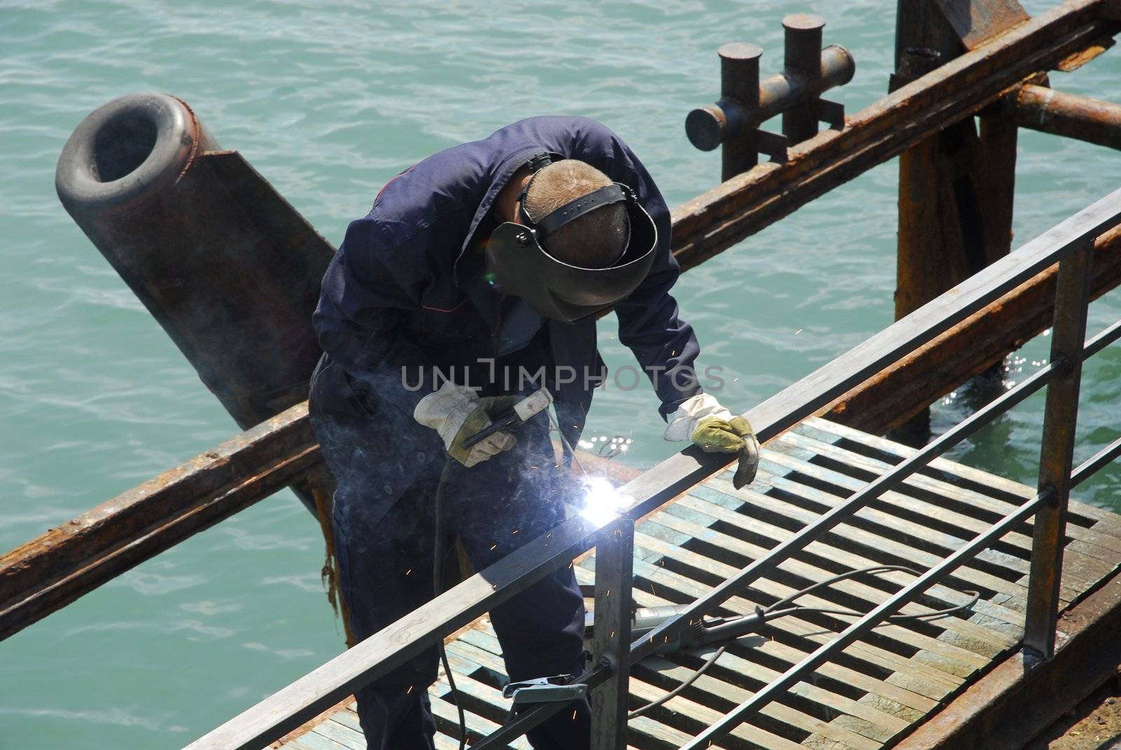 welding operator works on pier near the sea