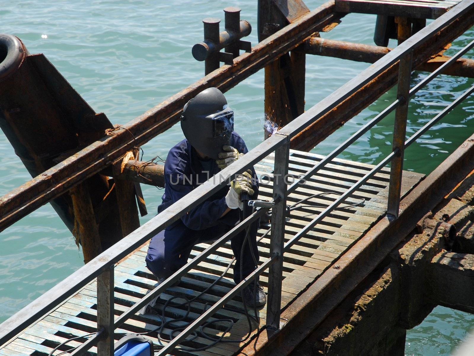 welding operator works on pier near the sea 