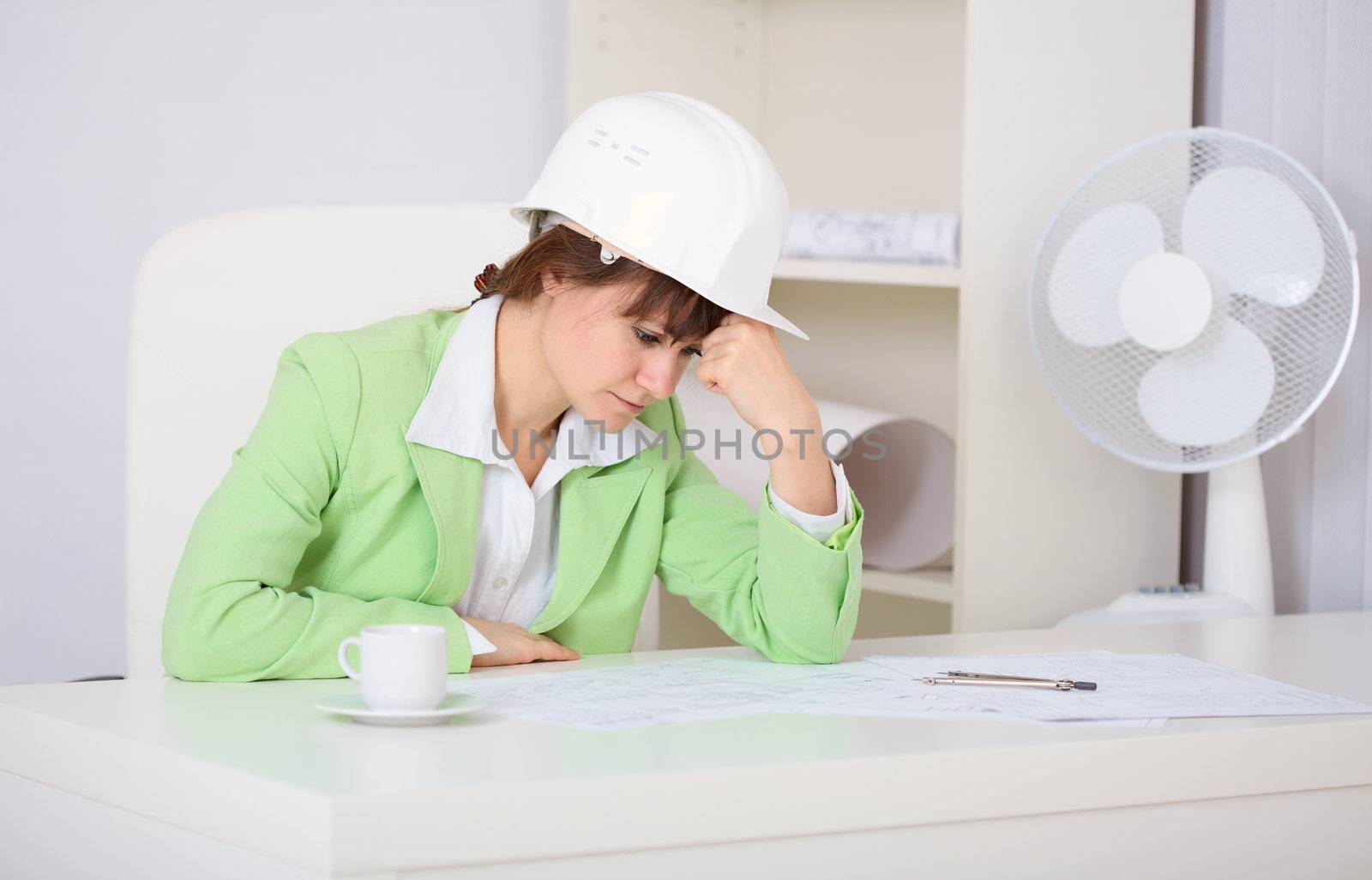 Tired woman engineer in helmet on the workplace