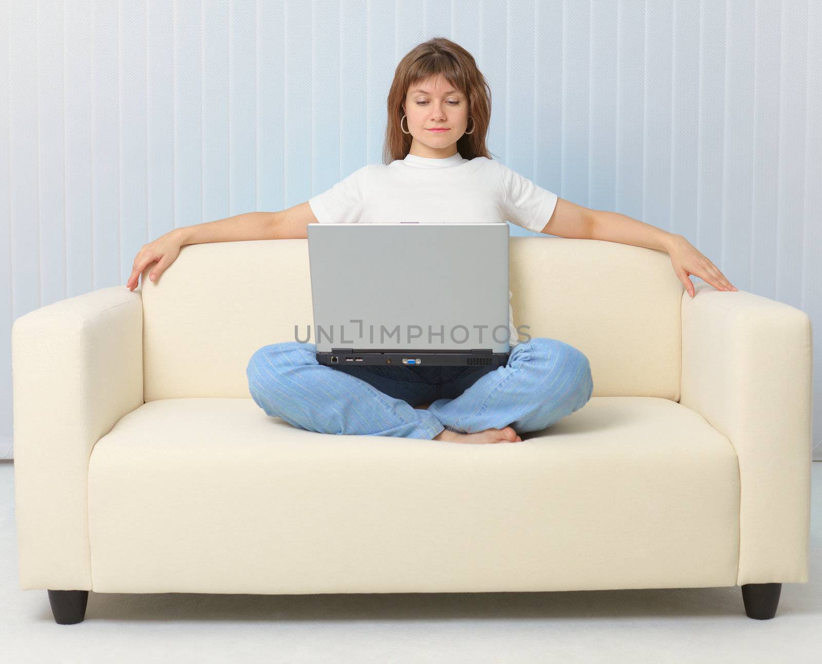 Beautiful girl looking movie sitting on couch with laptop by pzaxe