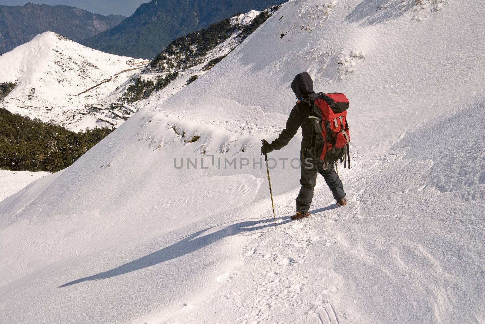 Man hiking on snow white mountain path.