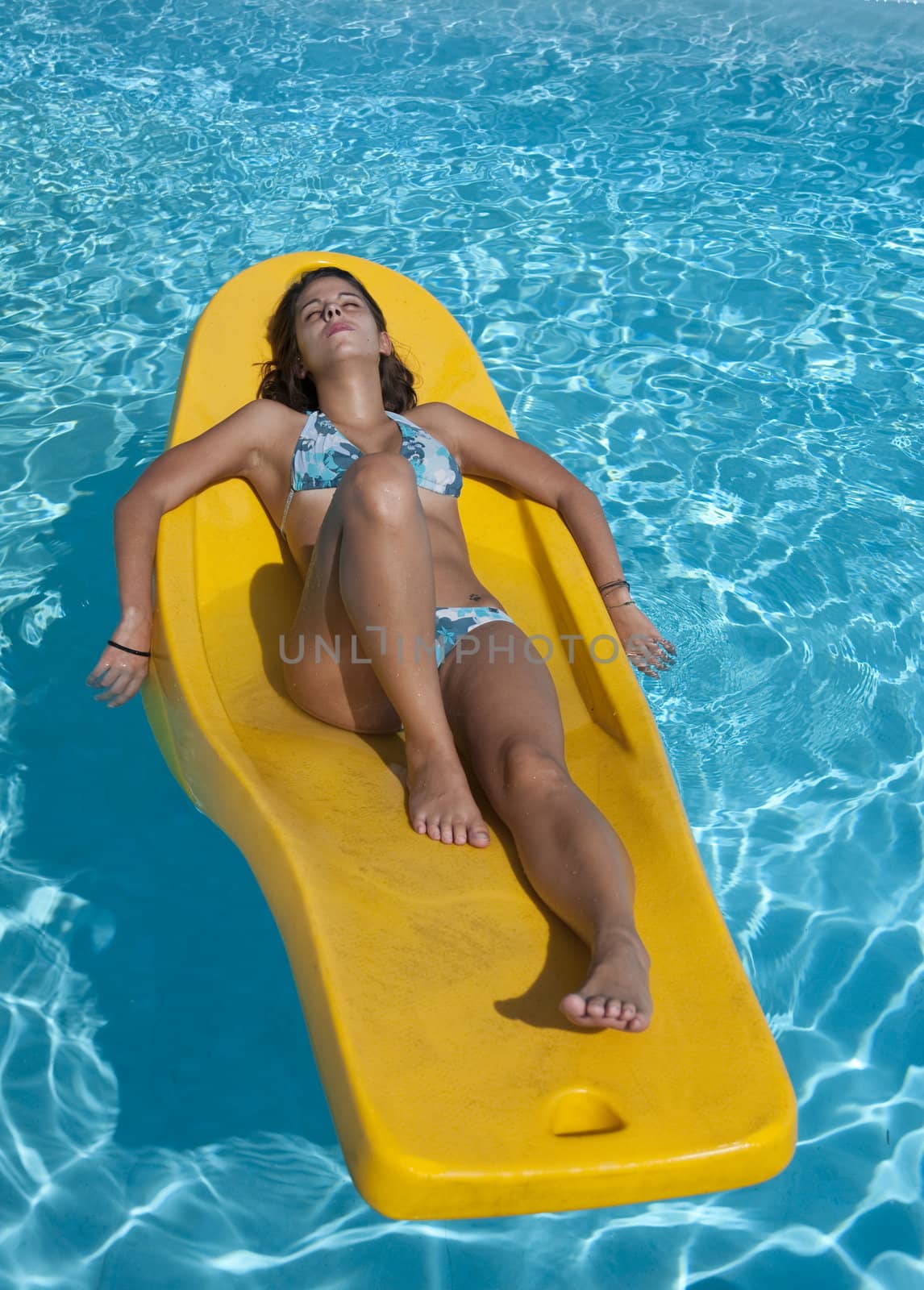 Young woman lying in the sun on a floating mattress