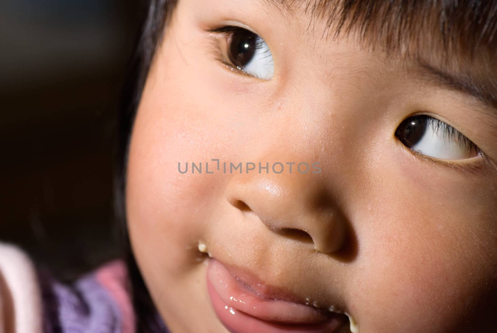 Portrait of Asian baby with greedy eating face.