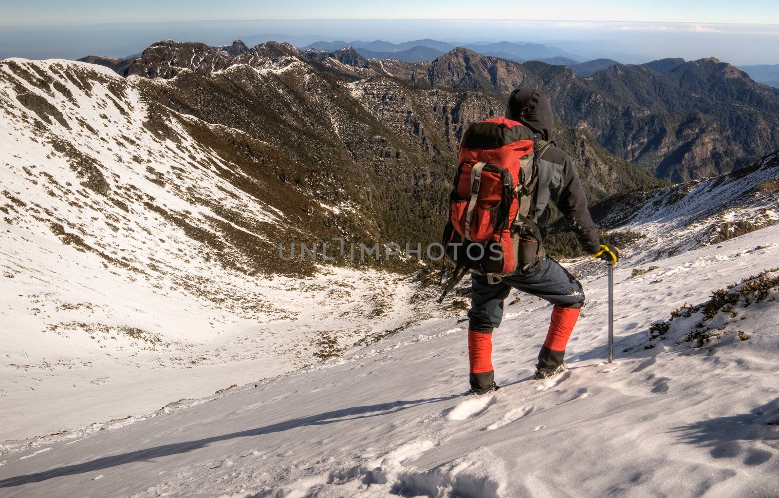 Man walk on snow slope of mountain with ice axe in beautiful sun shine day.