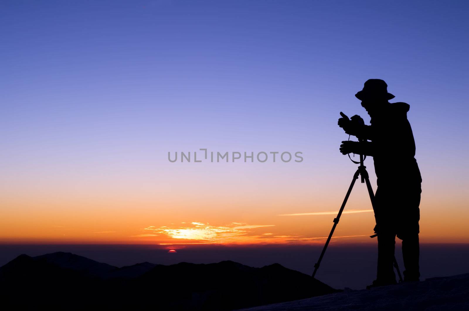 Outdoor photographer silhouette with dramatic color sunrise.
