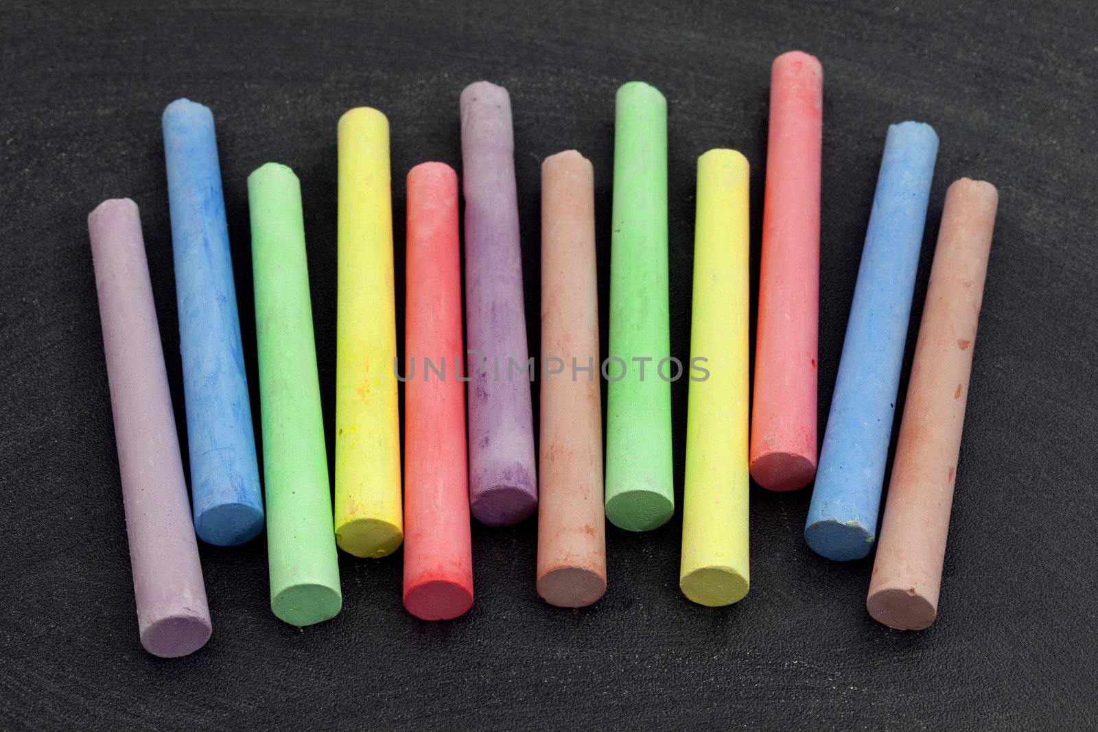 colorful chalk sticks on blackboard background