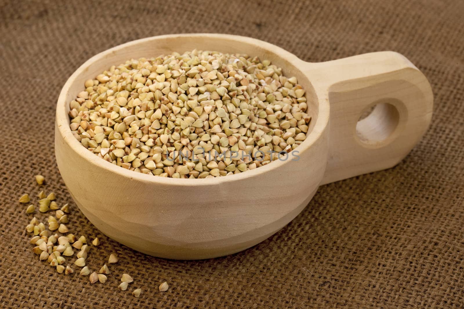 buckwheat groats on a rustic wooden scoop, burlap background