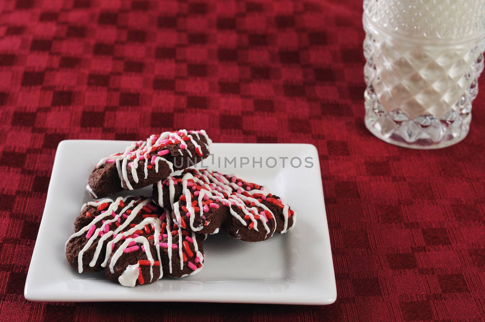 plate of cookies and a glass of milk on a red mat