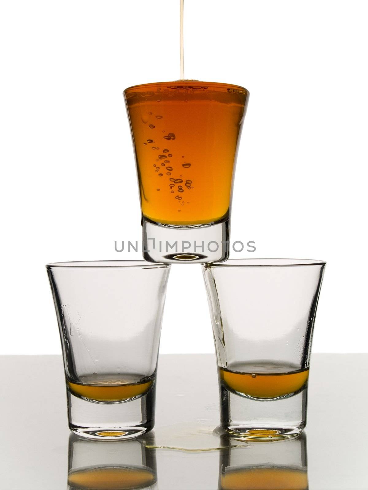 A shot being poured over two almost empty shots.