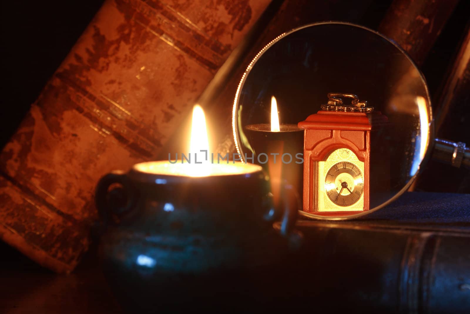 Vintage still life with old books, clock, magnifier glass and burning candle