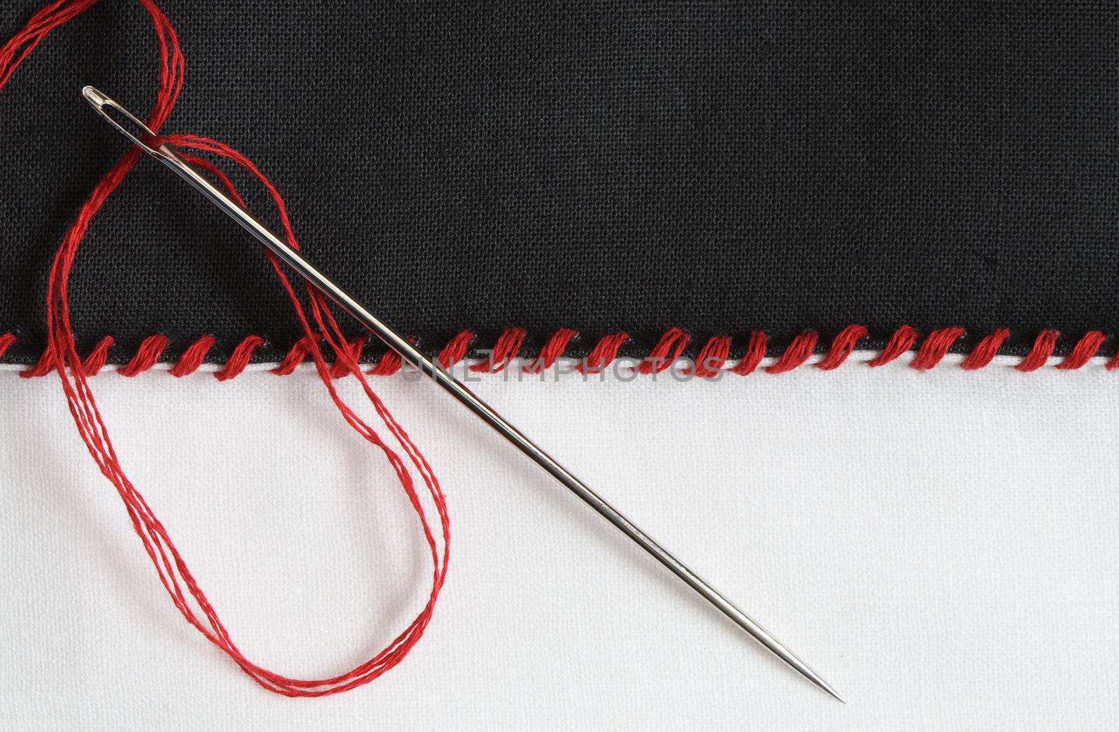 Closeup of black and white textile material jointed by red thread seam