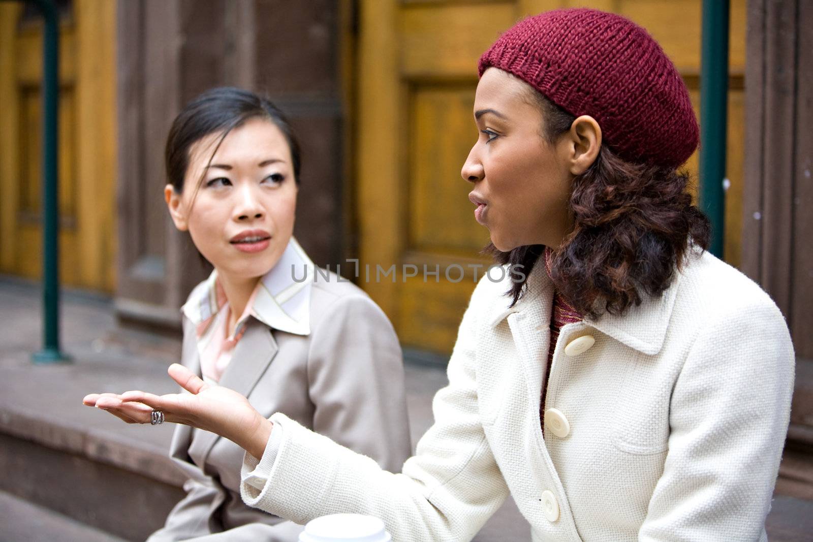Two business women having a casual chat or discussion in the city perhaps on their lunch break. Shallow depth of field.