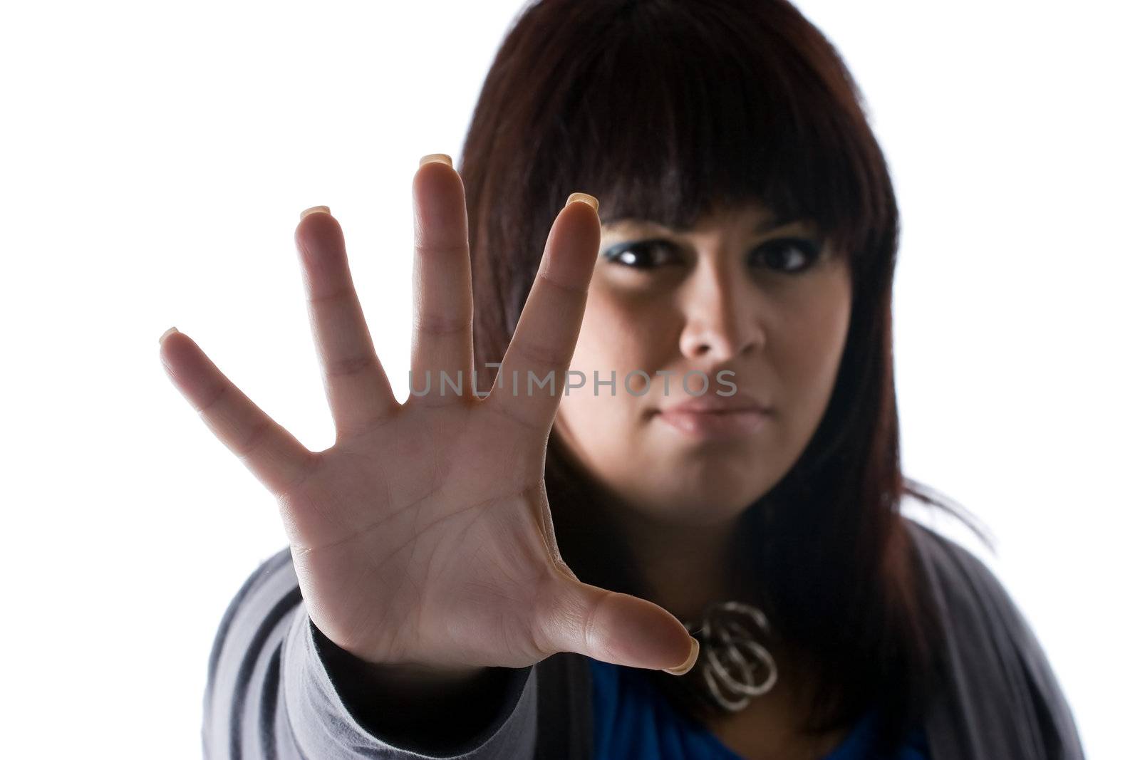 A woman holds up the palm of her hand in a defensive manner.  Shallow depth of field.