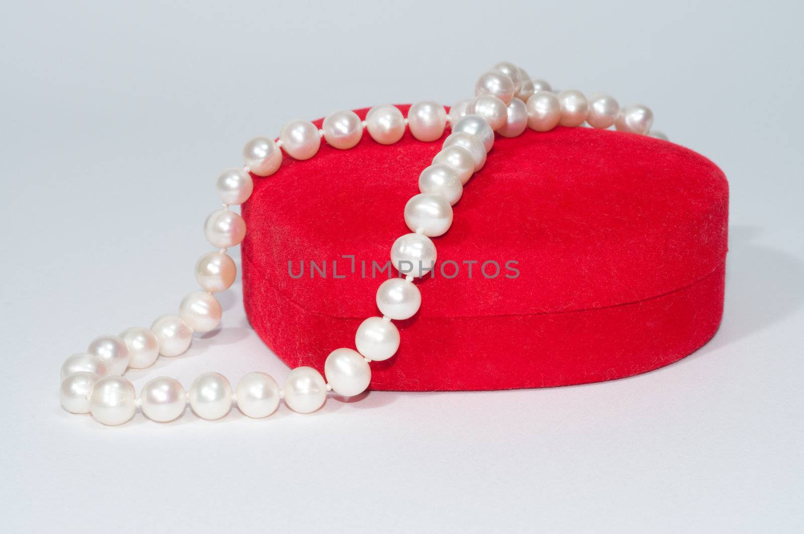 String of pearls on red velvet box  by Erchog