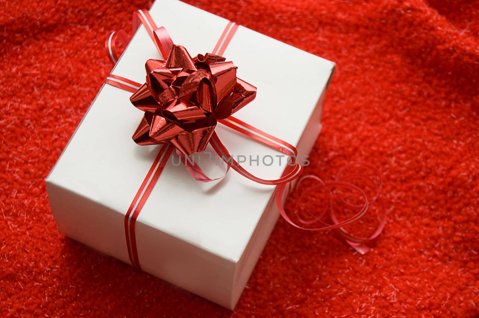 White gift box with red satin ribbon on red background