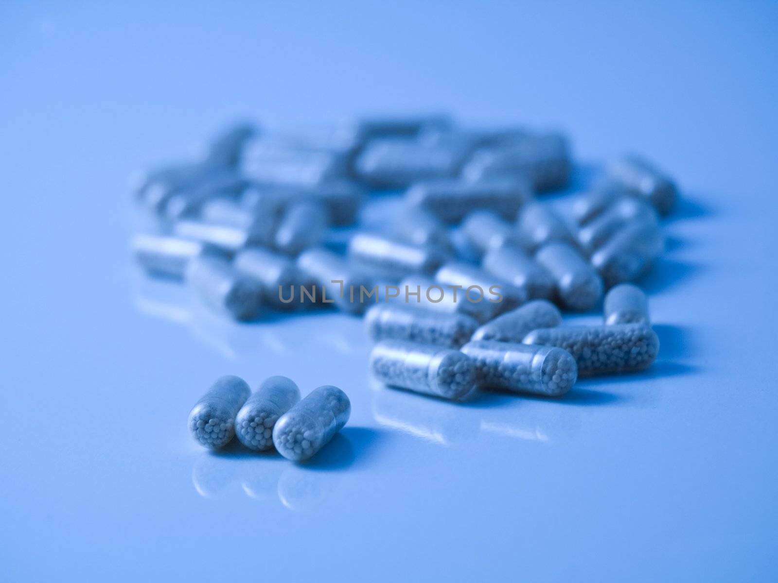 Blue tinted picture of  pills on reflective surface and with selective focus