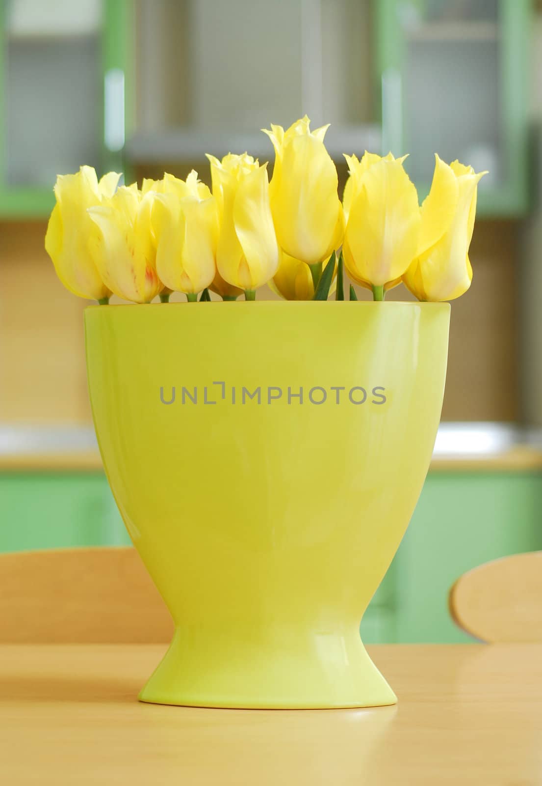 Yellow tulips on the table in green interior