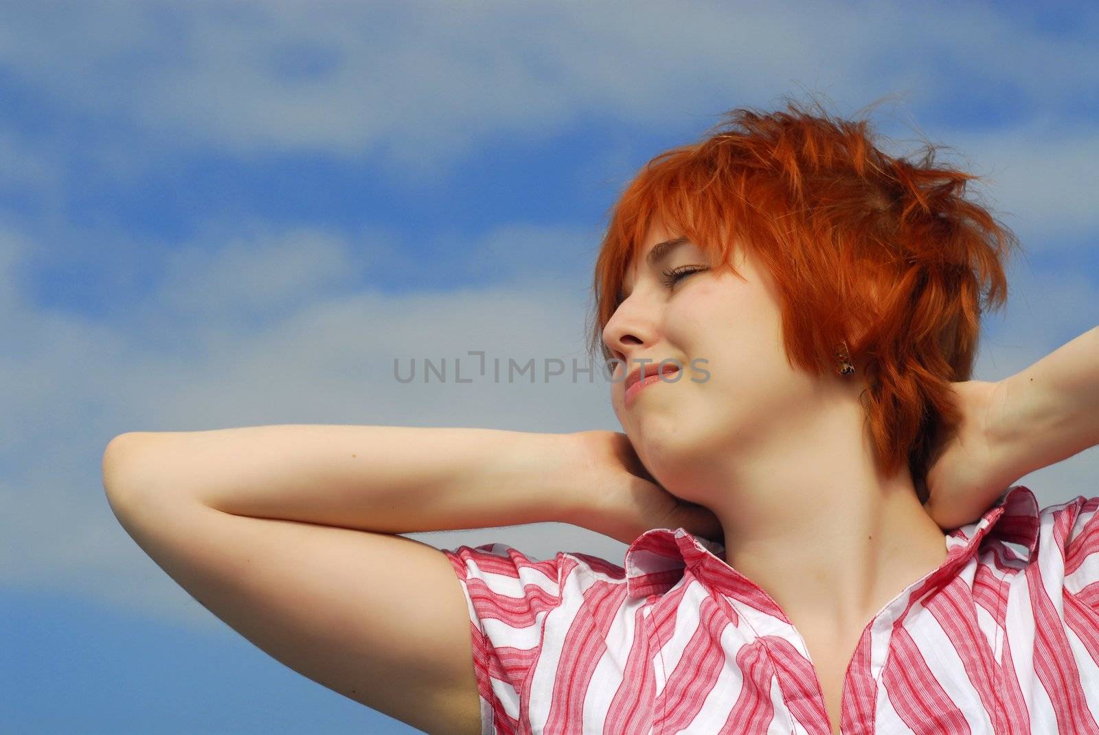 Smiling woman with red hair on blue sky background  