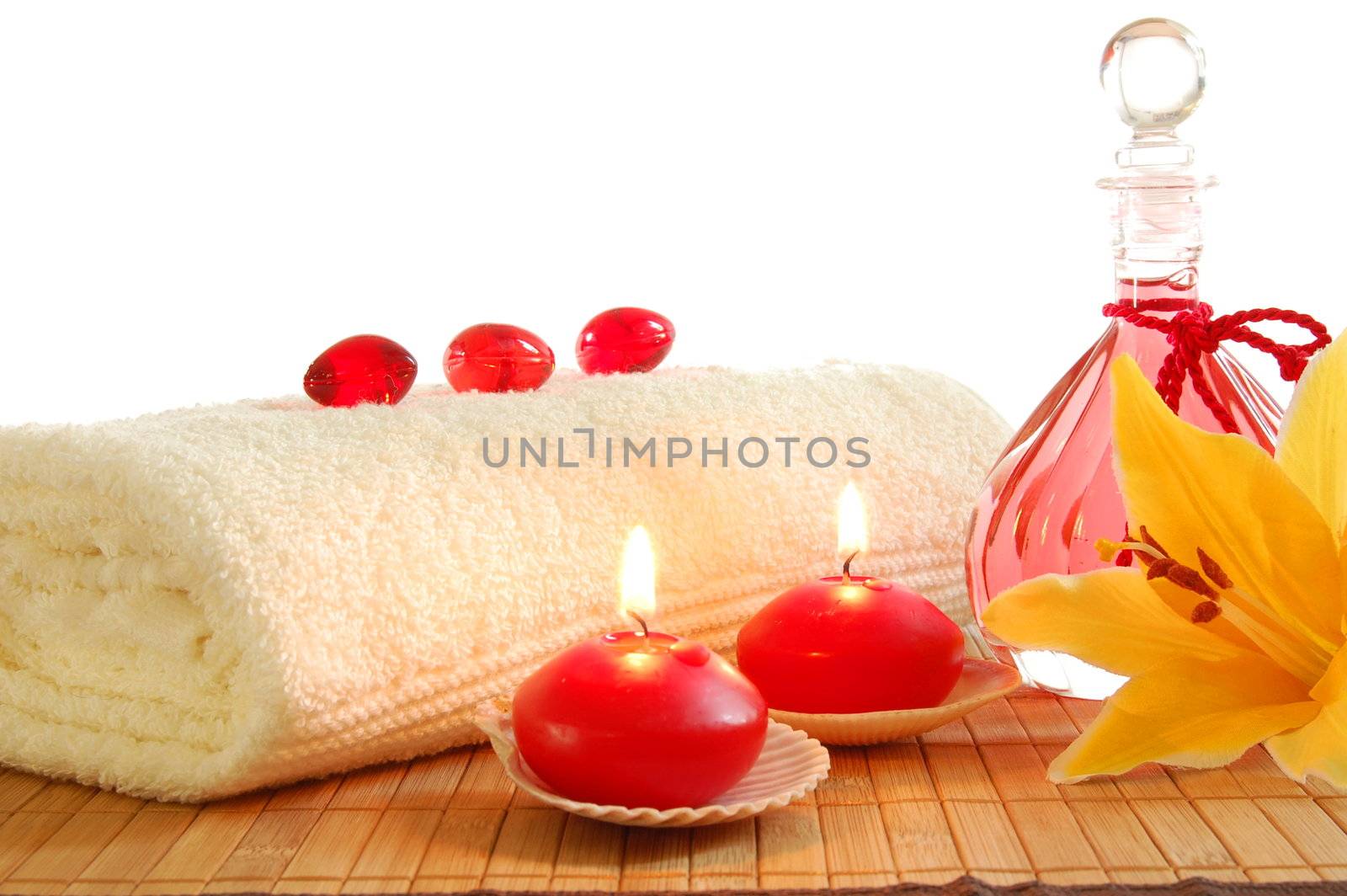 spa decoration with candles and red bottle with massage oil