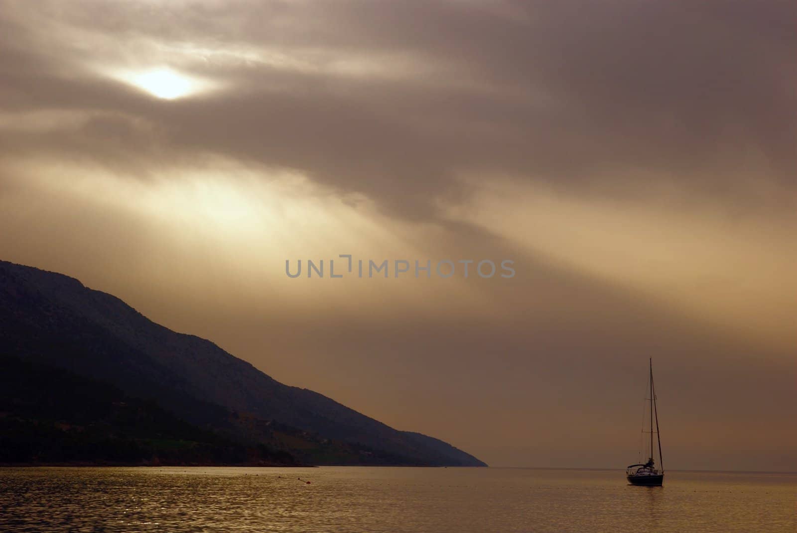 dramatically beautiful landscape with sea, ship and sun covered with clouds