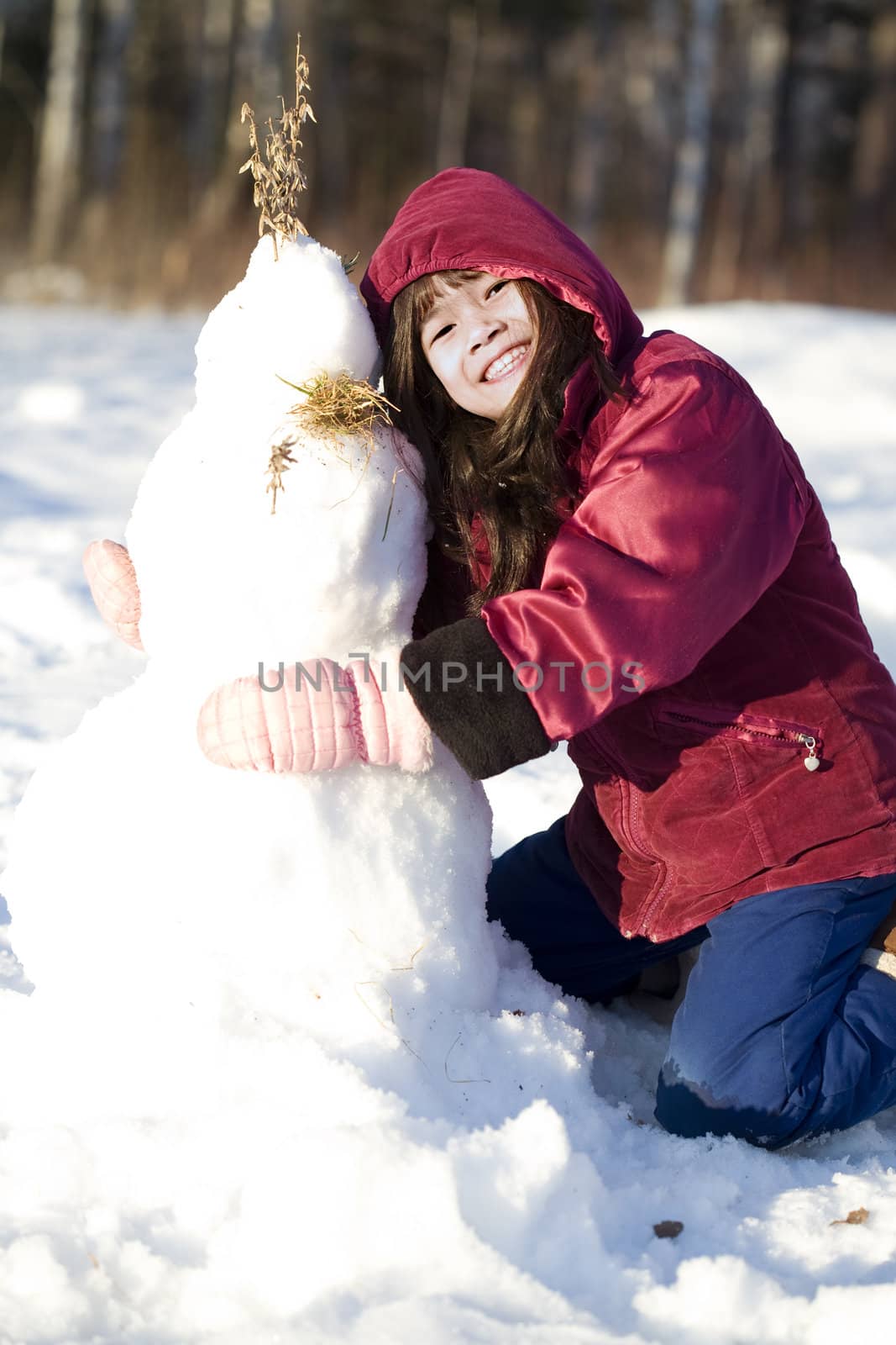 Girl playing in the snow making snowman