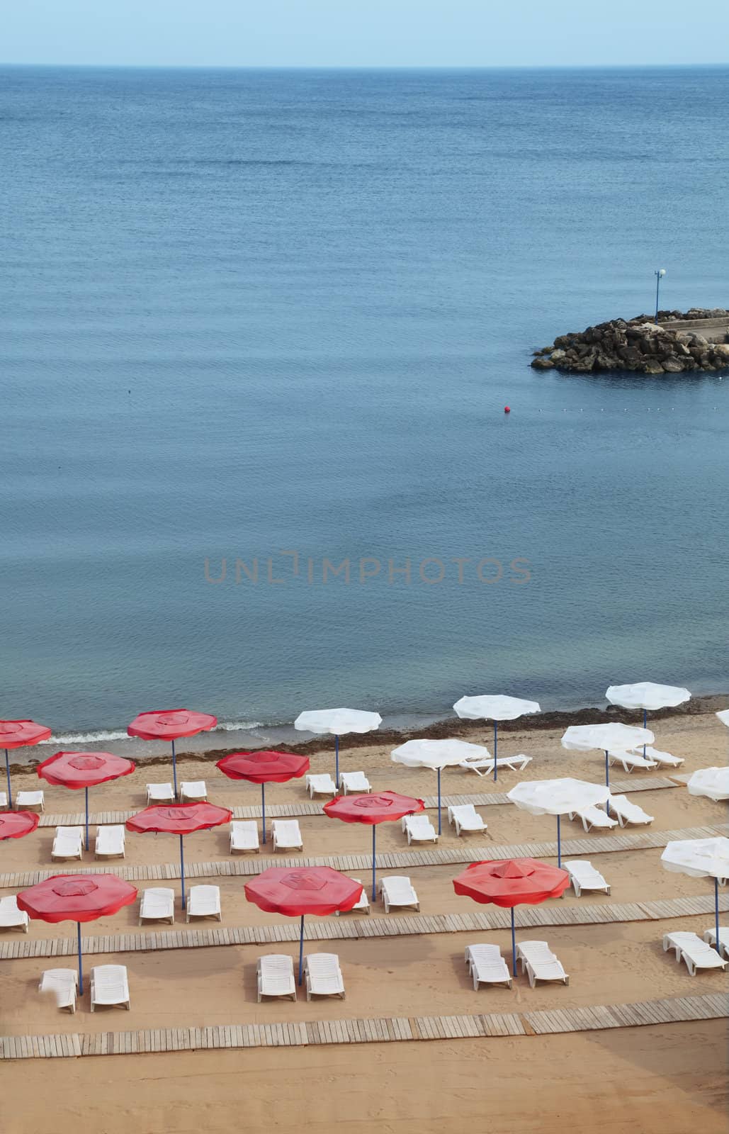 Empty beach with many sunbeds and parasols.