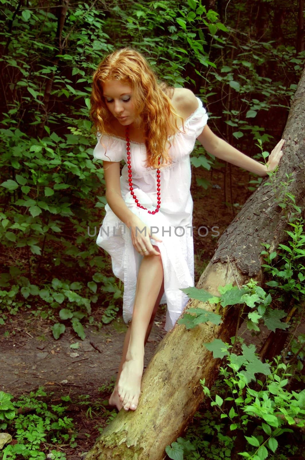 Redhead girl in deep woods posing near tree