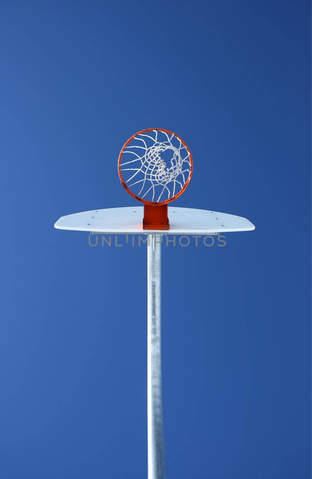 Orange basketball hoop against the blue sky, directly from below.