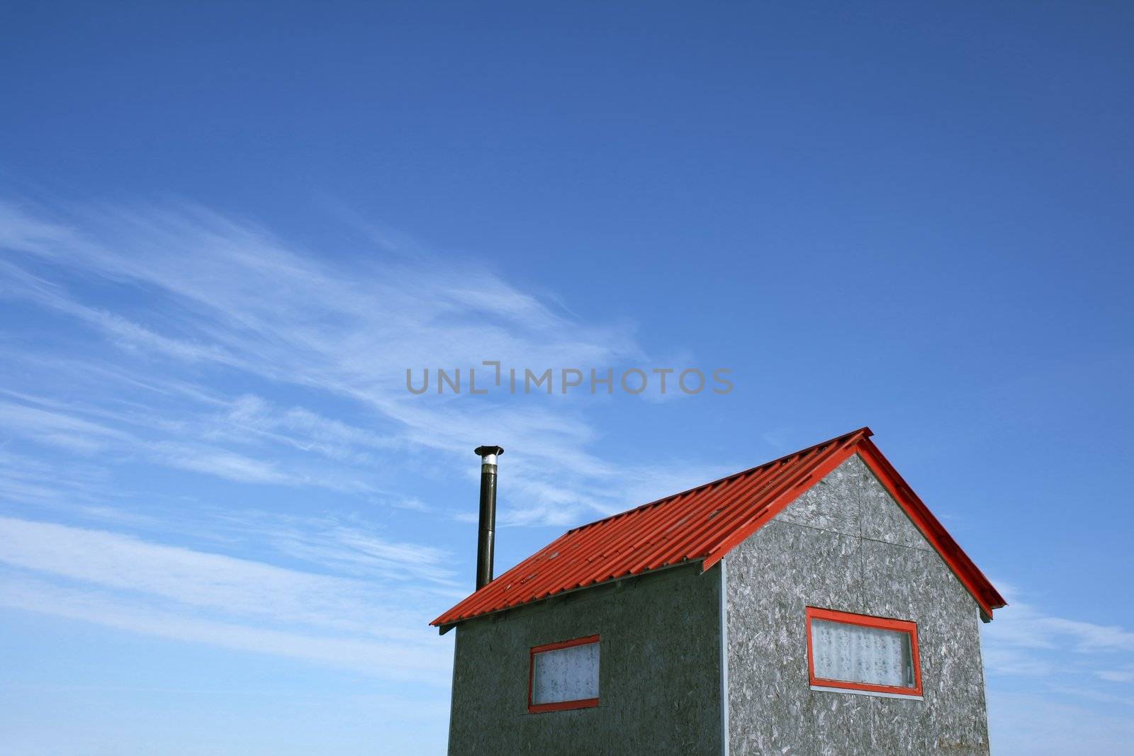 Little house with red roof and chimney and spacious blue sky (ice fishing hut).