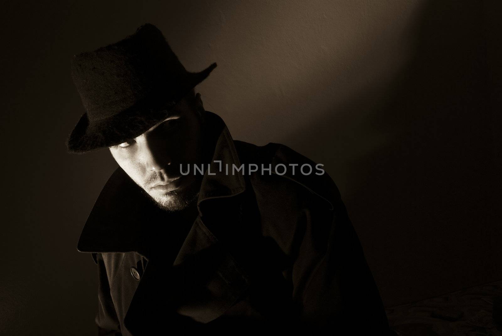 Sepia toned noir portrait of suspicious looking young man. Harsh highlights and shadows.