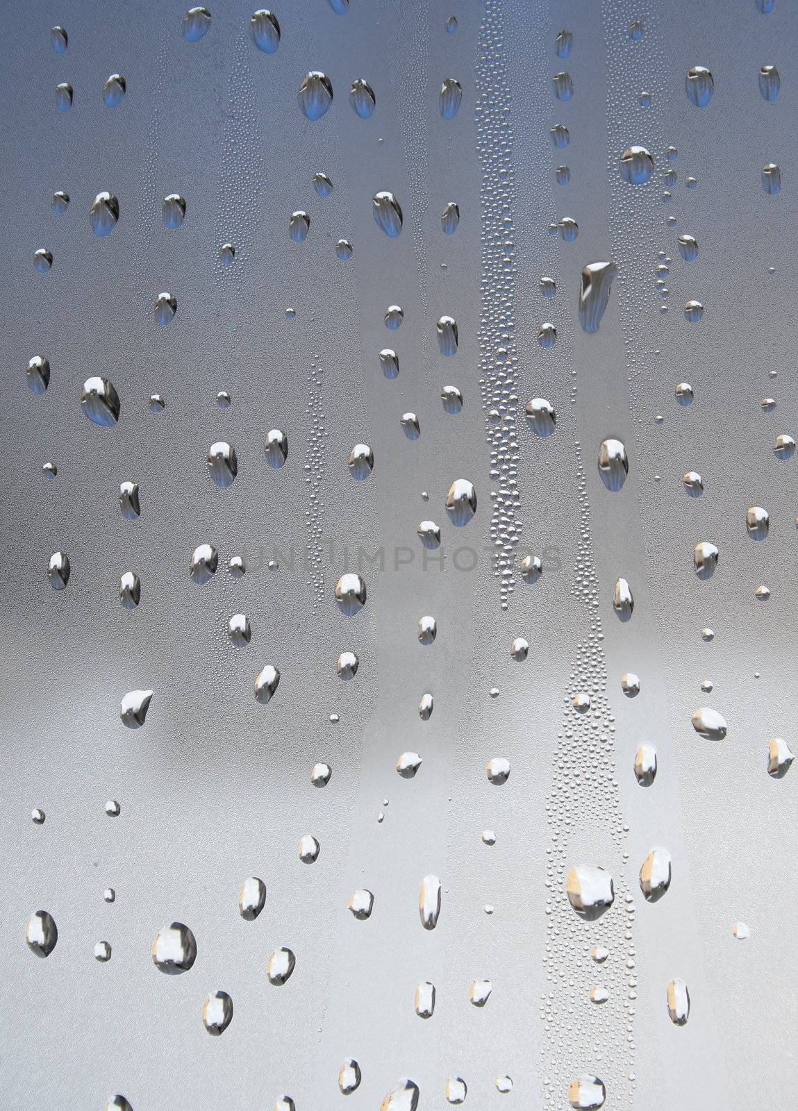 Water drops of metallic color on glass.
