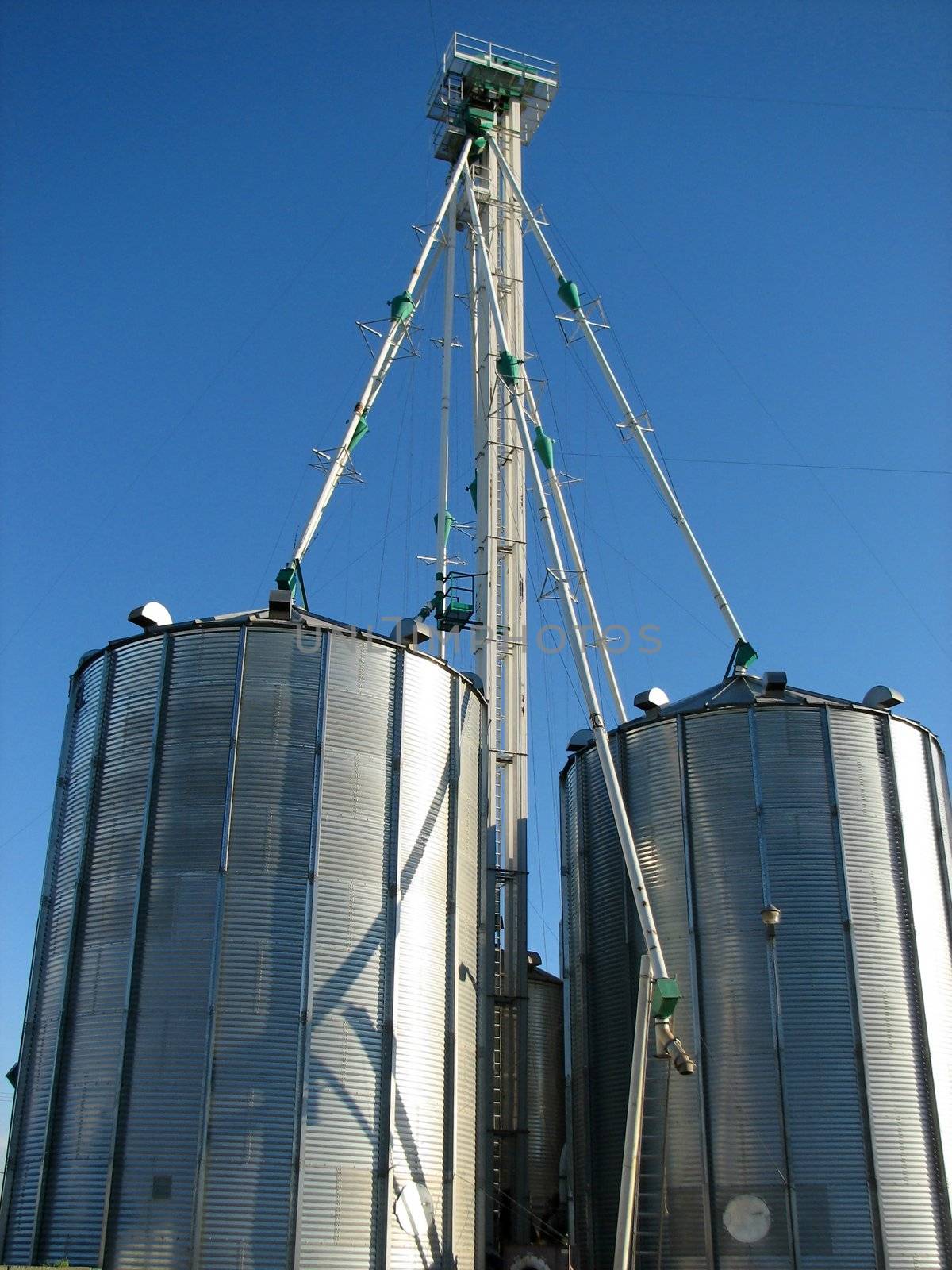Steel grain bins and blue sky by anikasalsera