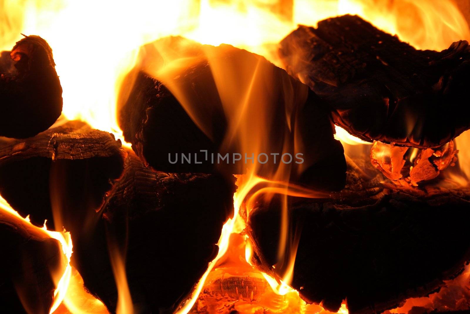 Warm fireplace - glowing wood logs and fire flames.