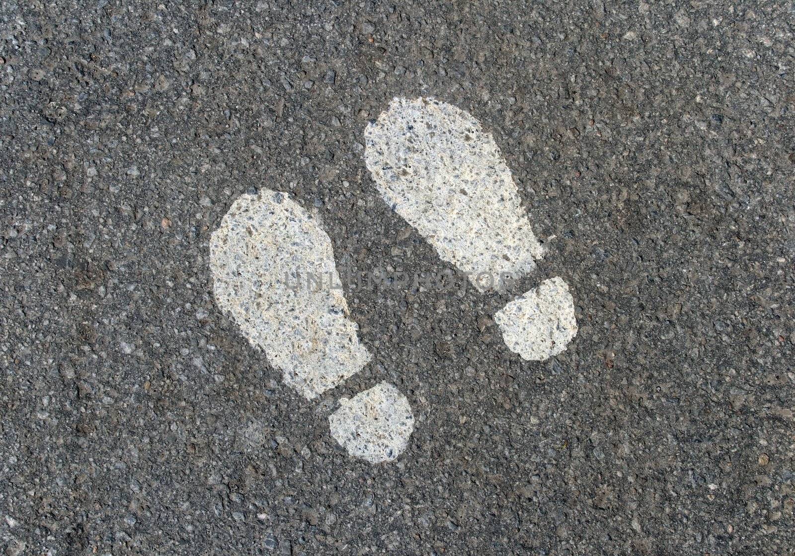 White painted footprints on asphalt road.