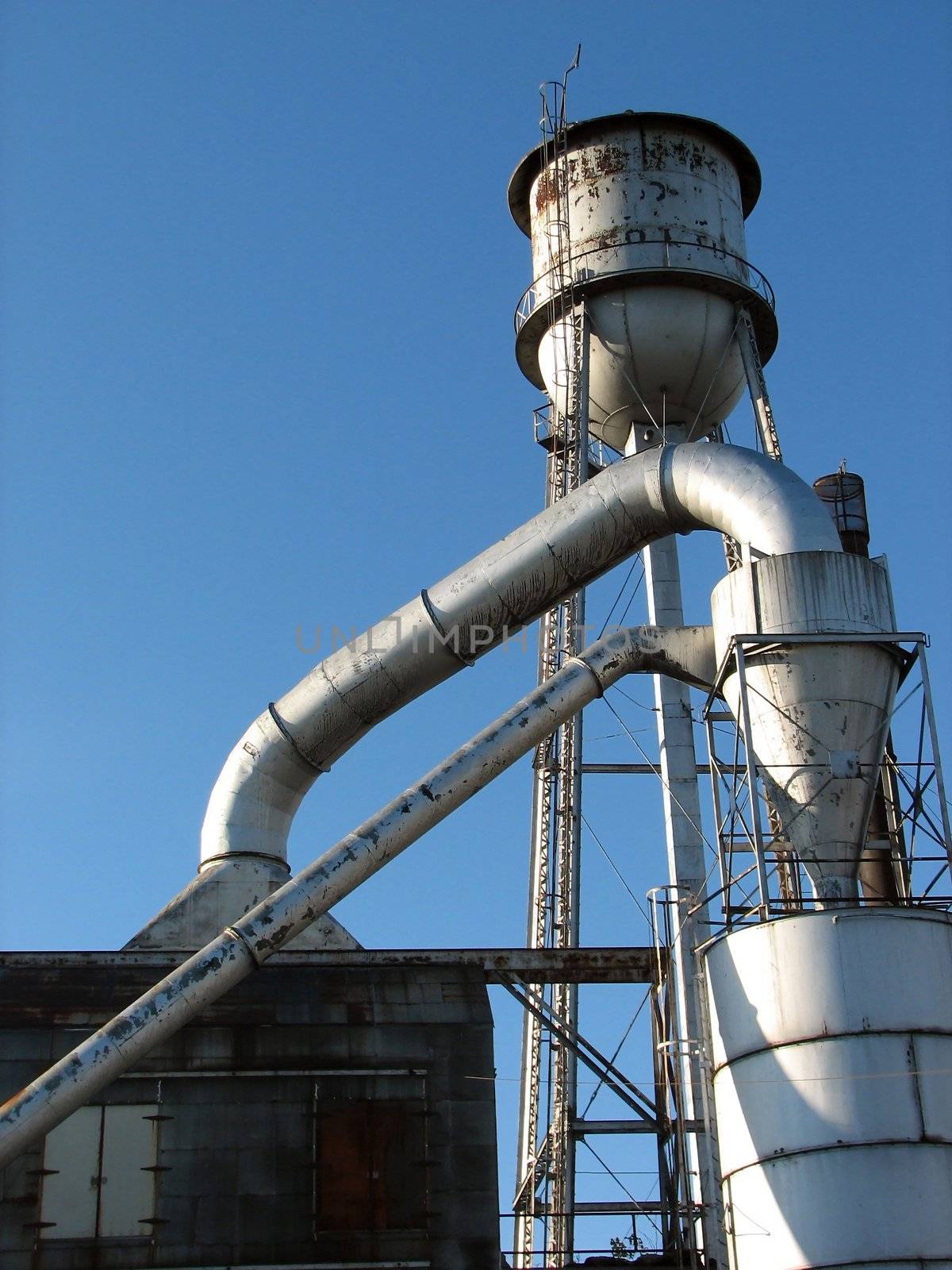 Shot of an old factory and water tower on a blue sky background.