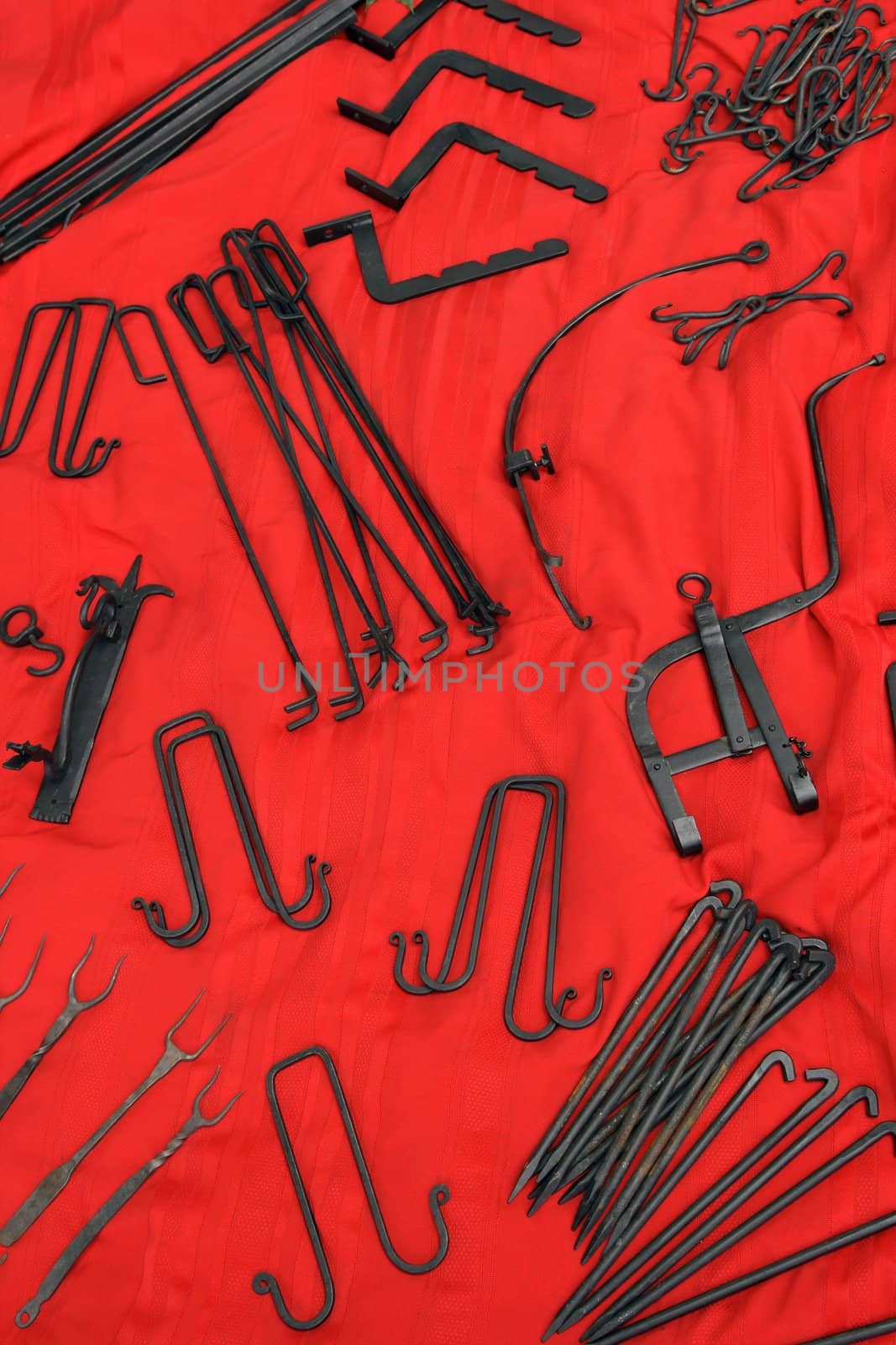 Old-fashioned wrought iron tools on red background.