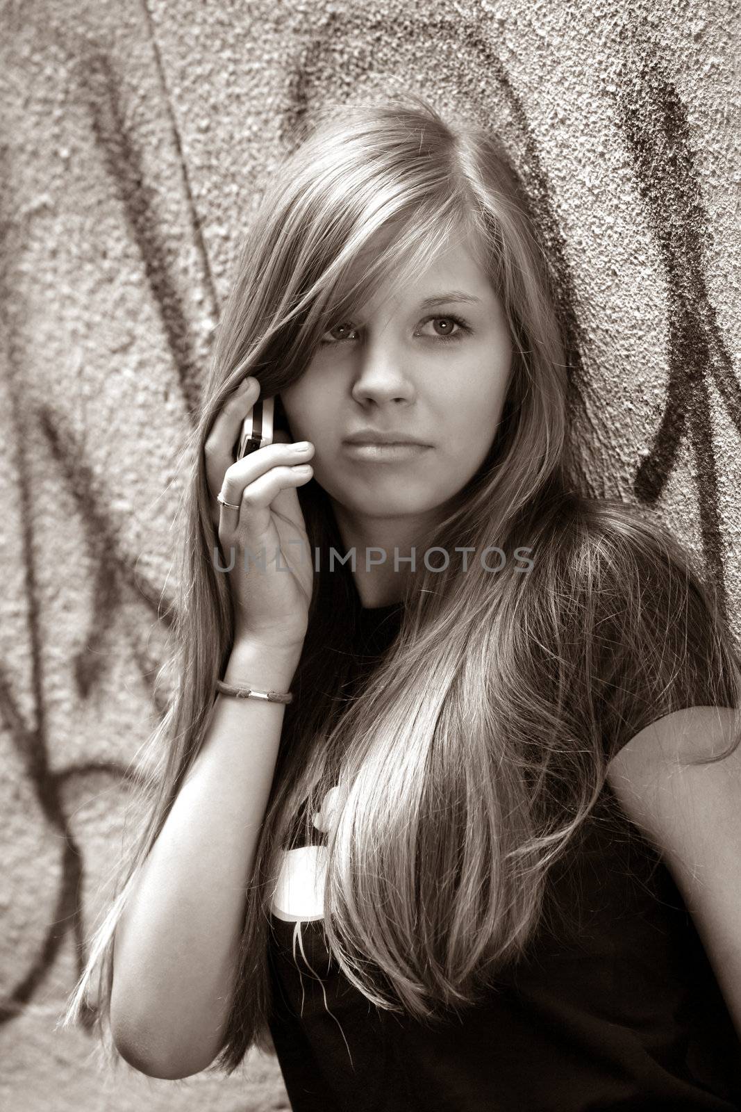 The girl - teenager with the phone on a background of a wall