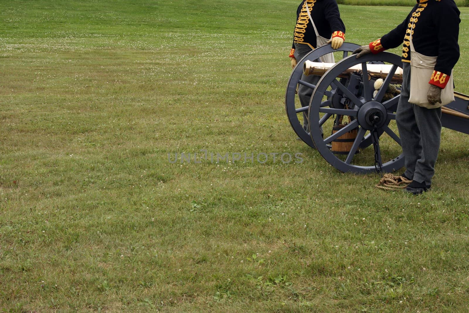 Soldiers in the uniform of the XIX century, with a field canon ready to shoot.