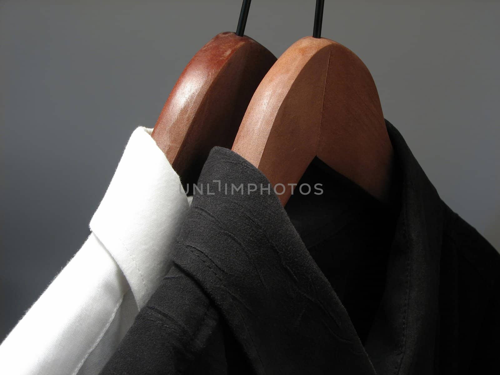 Stylish black and white shirts on wooden hangers.