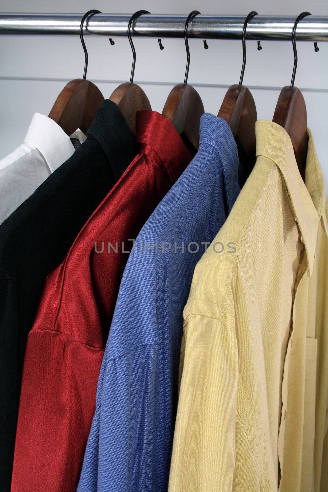 Shirts of different colors on wooden hangers.