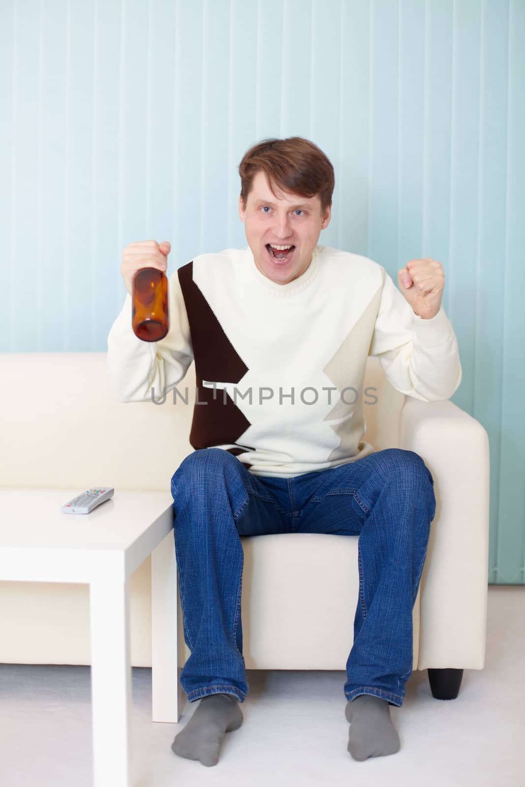 Football fan sitting on the sofa with a TV and beer