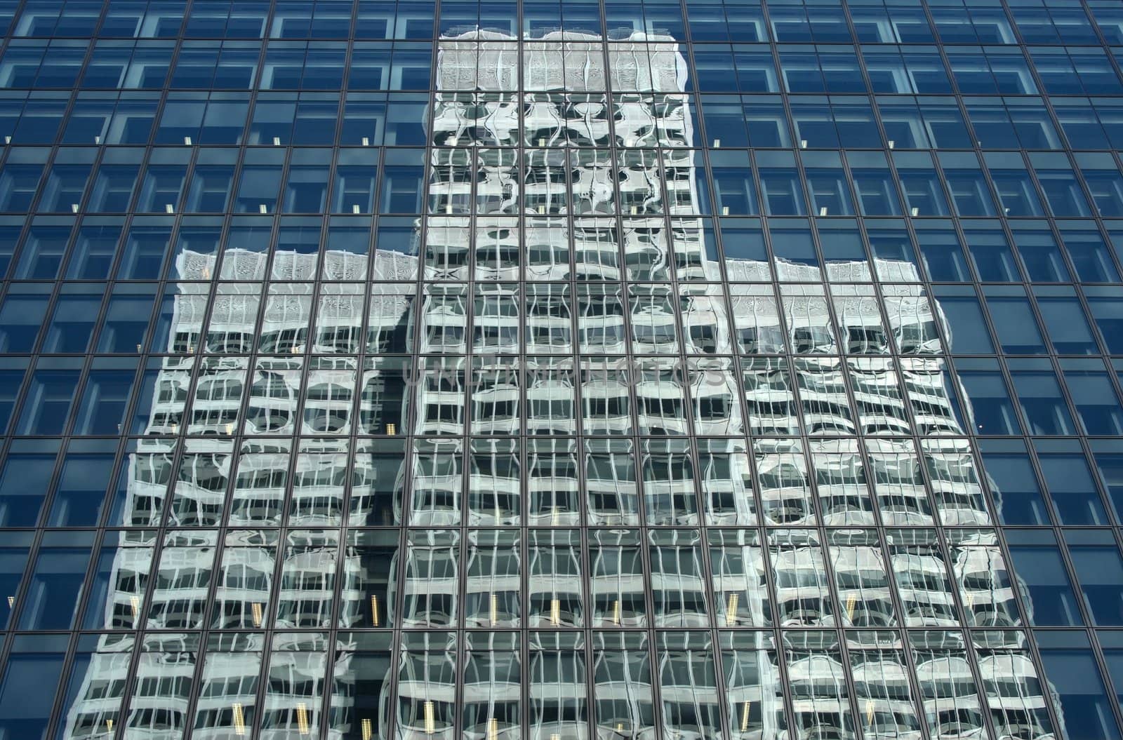 Skyscraper reflecting a white symmetrical office building.