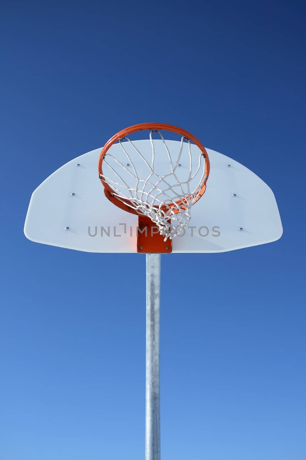 Basketball backboard, hoop and net against the blue sky.