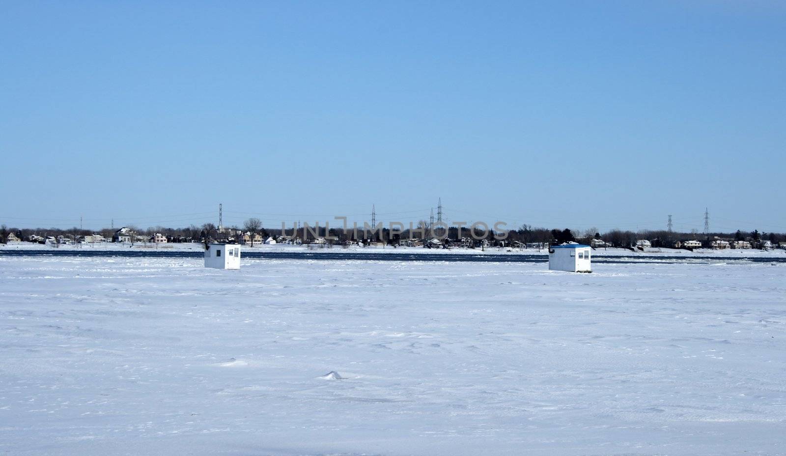 Ice fishing huts on a frozen river by anikasalsera